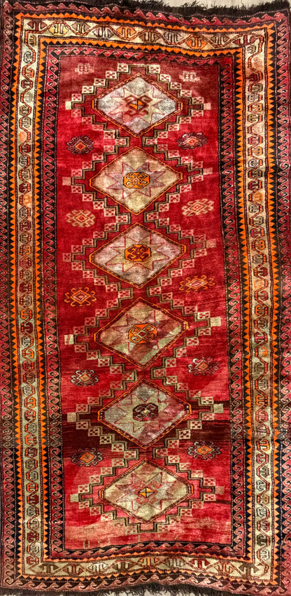 Red patterned rug with intricate designs on a plain background