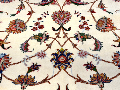 A close-up of an ornate floral patterned rug with a cream background and intricate multicolor motifs in red, blue, green, and gold.