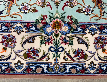 Close-up of an ornate floral patterned rug showing cream, blue, red, green, and tan woven details with a central medallion and border motifs.