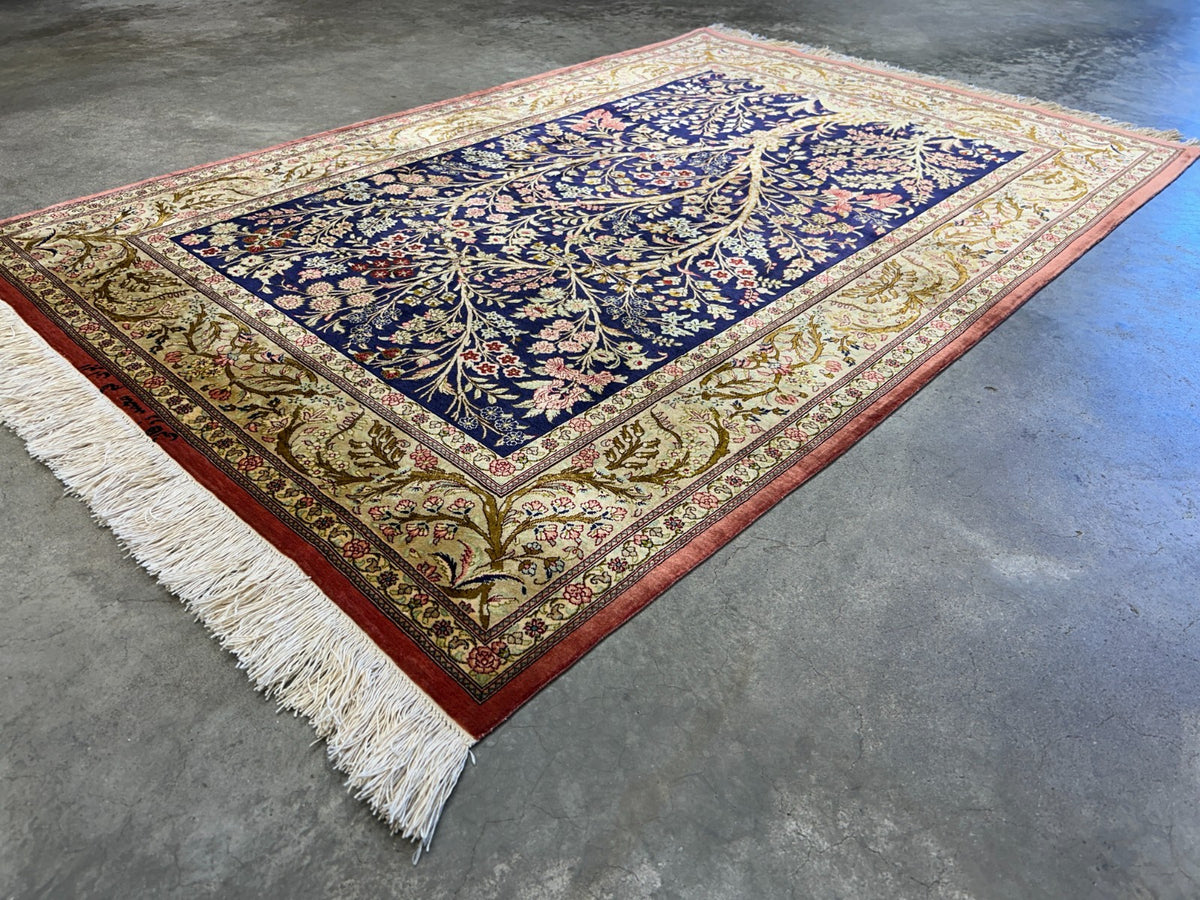 Decorative 3x5 silk Persian Qum rug with intricate patterns on a concrete floor