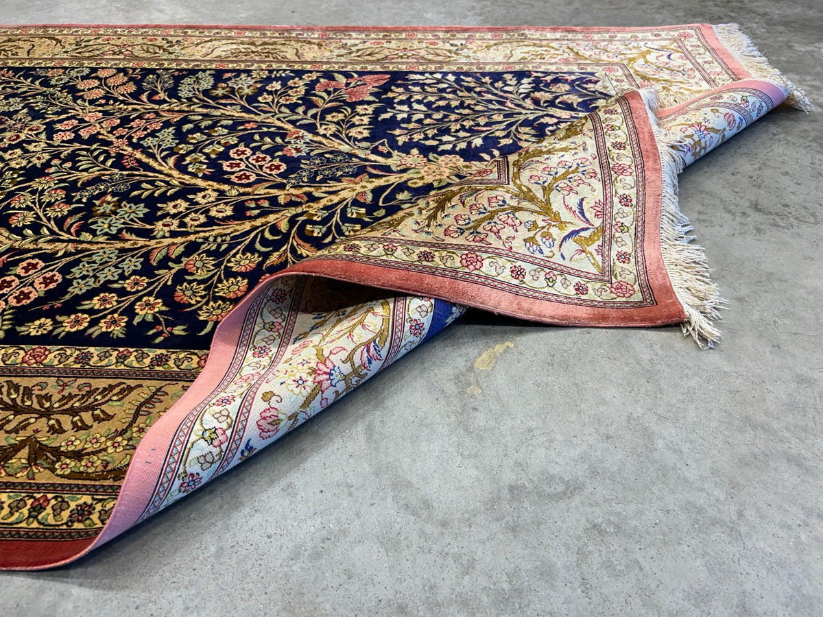 Decorative 3x5 Qum silk rug with intricate patterns on a concrete floor