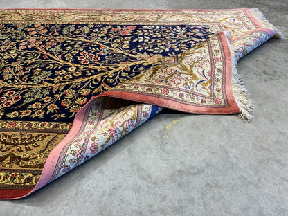 Decorative 3x5 Qum silk rug with intricate patterns on a concrete floor